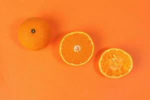 mandarijn- oranje fruit plak voor de helft geperst geëxtraheerd Aan oranje achtergrond foto