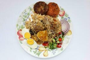 huis stijl schapenvlees kacchi biryani met aardappel karbonade tomaat komkommer ui salade Aan oud stijl bord over- wit achtergrond foto