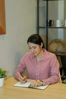 jong zuiden oosten- Aziatisch vrouw bedrijf kantoor Bij cafe stoel tafel werk studie lezen foto