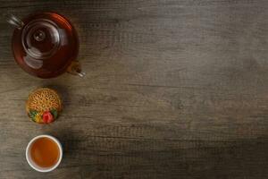 kleurrijk bloem versierd mooncake besnoeiing plak voor de helft laag Chinese midden herfst festival Aan glas theepot wit keramisch theekopje over- rustiek hout grens kopiëren tekst ruimte foto