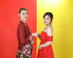twee Aziatisch vrouw traditioneel kebaya en modern jurk rood geel papier achtergrond ontmoeten Super goed foto