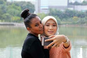 twee vrouw Maleis Chinese Indisch Aziatisch Maleisisch buitenshuis groen park meer natuur selfie smartphone camera zelf portret foto