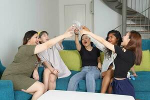 jong Aziatisch vrouw groep praten roddel babbelen zingen drinken proost partij pret genieten emotie Aan blauw leven kamer sofa foto