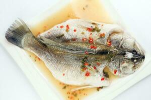 Thais stijl stoom- zee bas barramundi met citroen knoflook chili Doorzichtig saus Aan wit portie schotel foto