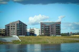 meerdere verdiepingen woon- gebouwen Aan de rivier- bank met reflecties Aan water en blauw lucht met wolken Aan een warm zomer dag foto