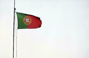 Portugees vlag golvend in de wind tegen een Doorzichtig lucht foto