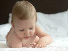 blond baby meisje aan het liegen Aan bed foto