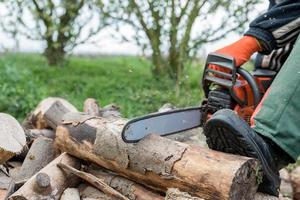 man zaagt brandhout met een rode kettingzaag foto