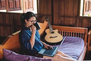 vrouw met een kopje koffie zittend op een vloer in huis notities opschrijven geopende laptop voor haar thuiskantoor concept foto