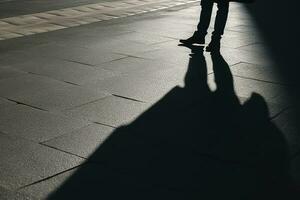 donker schaduw van een eenzaam persoon Aan de grond in de straat. vreemdeling met een sigaret. ongerustheid, depressie, eenzaamheid, angst concept, genereren ai foto