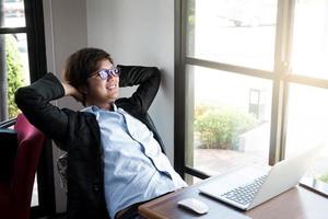 jonge zakenman ontspannen aan zijn bureau in de coffeeshop foto