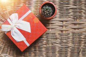 rode geschenkdoos met wit lint op geweven bamboe houten achtergrond, gezellig en warm welkom thuis concept foto