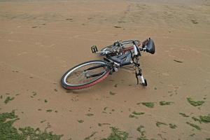 mountainbike ligt op het zand op een leeg strand foto