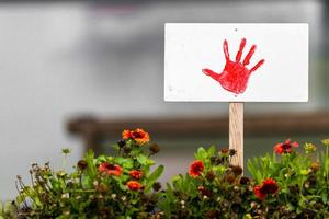 schild met geschilderde rode hand staat in een bloembed met kopie ruimte foto