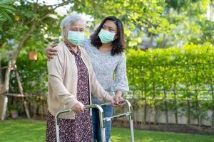 aziatische senior of oudere oude dame vrouw lopen met rollator en het dragen van een gezichtsmasker ter bescherming van de veiligheid infectie covid 19 coronavirus foto