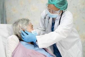 arts die een stethoscoop gebruikt om te controleren Aziatische senior of oudere oude dame vrouw patiënt draagt een gezichtsmasker in het ziekenhuis voor bescherming van infectie covid 19 coronavirus