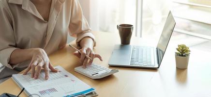 zakenvrouw werken in financiën en boekhouding analyseren financiële begroting met rekenmachine en laptop op kantoor foto