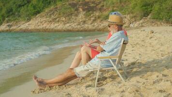 een paar van ouderen zittend in stoelen Bij de strand aan het kijken de zon en de zee Aan hun zomer vakantie en ze glimlach en genieten hun vakantie. foto