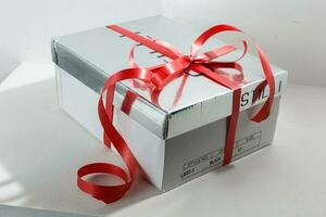 zilver geschenk doos Aan wit achtergrond. zilver geschenk doos met rood lintje. foto