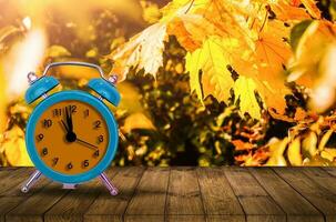 oud klok Aan herfst bladeren Aan houten tafel Aan natuurlijk achtergrond foto