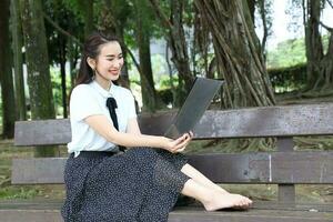 jong Aziatisch Chinese vrouw buitenshuis Aan park bank houden het dossier boek map lezen zien glimlach foto