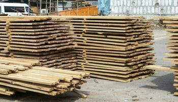 stapel van gestapeld houten planken Bij een bouw plaats. houten planken, timmerhout. industrieel omrand hout. houten spanten voor de reparatie of bouw van een privaat huis. dakbedekking en schrijnwerkerij timmerhout. foto