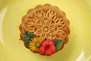 kleurrijk bloem versierd maan taart Chinese midden herfst festival thee Aan geel keramisch bord foto