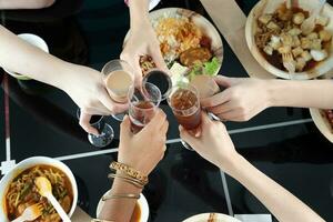 jong zuidoosten Aziatisch vrouw groep praten vieren aan het eten genieten van voedsel rijst- kerrie noodle kip drinken proost Aan dining tafel top visie foto