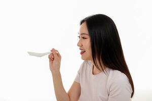 mooi jong zuiden oosten- Aziatisch vrouw Holding Chinese leeg eetstokje soep lepel kom werktuig doen alsof acteren poseren zien eten smaak voeden aanbod tevredenheid lekker wit achtergrond gelukkig foto