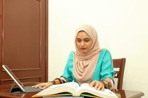 jong Aziatisch Maleis moslim vrouw vervelend hoofddoek Bij huis kantoor leerling zitten Bij tafel computer boek het dossier papier studie werk foto