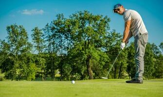 Kaukasisch golf speler gebruik makend van putter club foto