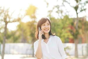 portret mooi jong Aziatisch vrouw met slim mobiel telefoon in de omgeving van buitenshuis natuur visie in een zonnig zomer dag foto