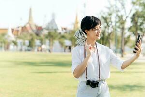 portret mooi jong Aziatisch vrouw met smartphone Aan zomer vakantie vakantie reis met de groots paleis in een achtergrond Bij Bangkok, Thailand foto