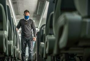 openbaar vervoer passagier in gezicht masker wandelen langs trainer bus steeg foto