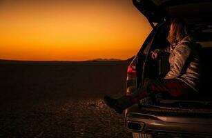 vrouw genieten van toneel- zonsondergang van haar auto foto