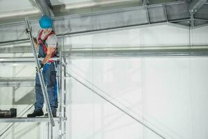 arbeider Aan stellingen afwerking magazijn gebouw foto