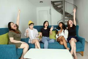 jong Aziatisch vrouw groep praten roddel babbelen zingen partij pret genieten emotie Aan blauw leven kamer sofa foto