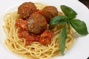 gekookt spaghetti tomaat gehaktbal saus kaas poeder basilicum Aan wit bord houten tafel foto
