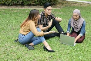 jong Aziatisch verschillend etnisch Maleis chinees Mens vrouw werkzaamheid levensstijl leerling opleiden baan bedrijf zitten Aan gras bespreken foto