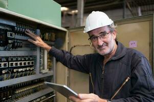 senior ingenieur inspecteert de elektrisch systeem en reparaties de mechanisch systeem in de machine controle kastje. in bestellen voor de machine naar terugkeer naar normaal operatie foto