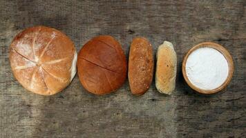 vers gebakken brood brood bun rollen ronde lang mengen waarheid meel in houten kom Aan houten over- rustiek houten achtergrond foto