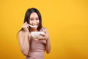 mooi jong zuiden oosten- Aziatisch vrouw Holding ruggegraten leeg eetstokje Chinese soep lepel kom werktuig doen alsof acteren poseren zien eten smaak geur voeden aanbod tevredenheid lekker geel oranje achtergrond foto