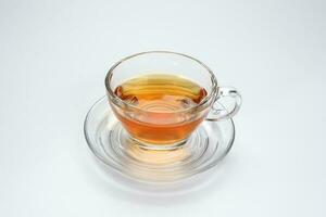 Doorzichtig licker thee in een transparant glas kop schotel Aan wit achtergrond foto