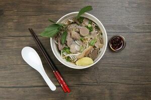 Vietnamees poh rundvlees noedels soep bouillon met rundvlees bal borst pens maag onderdelen geweest spruit Thais basilicum limoen in kom Aan houten tafel eetstokjes lepel saus foto