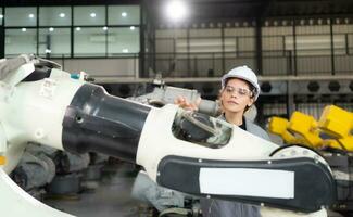 een vrouw ingenieur installeert een programma Aan een robotica arm in een robot magazijn. en test de operatie voordat Bezig met verzenden de machine naar de klant. foto