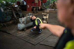 de technicus team leider moedigt aan de team wie zijn moe van moeilijk werk. in repareren oud machinerie naar terugkeer naar normaal operatie in de van het bedrijf oud machinerie magazijn foto