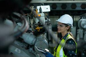 een vrouw ingenieur installeert een programma Aan een robotica arm in een robot magazijn. en test de operatie voordat Bezig met verzenden de machine naar de klant. foto