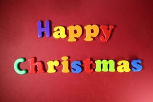 gelukkig Kerstmis teken Aan rood papier achtergrond kleur plastic alfabet foto