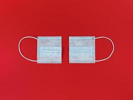 medisch wegwerp gezichtsmasker in tweeën gesneden op rode achtergrond foto