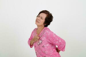 ouderen Aziatisch Chinese vrouw Aan wit achtergrond verdrietig van streek pijn hand- Aan borst foto